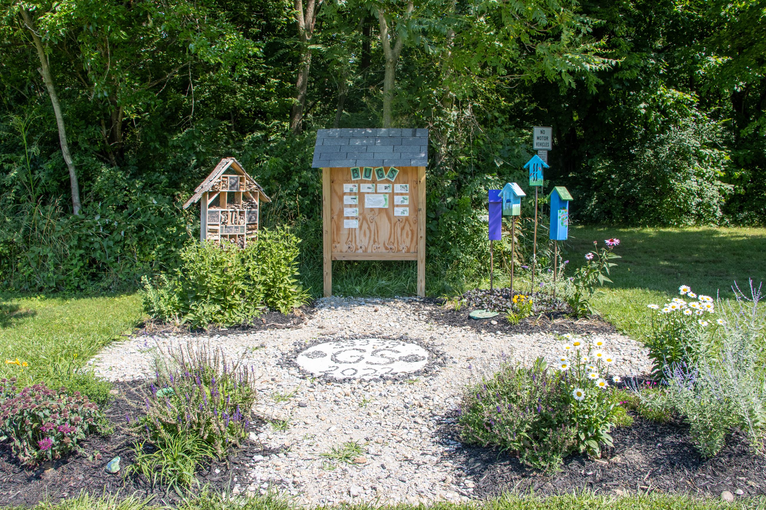 Outdoor classroom with educational message board, plants, and animal shelters
