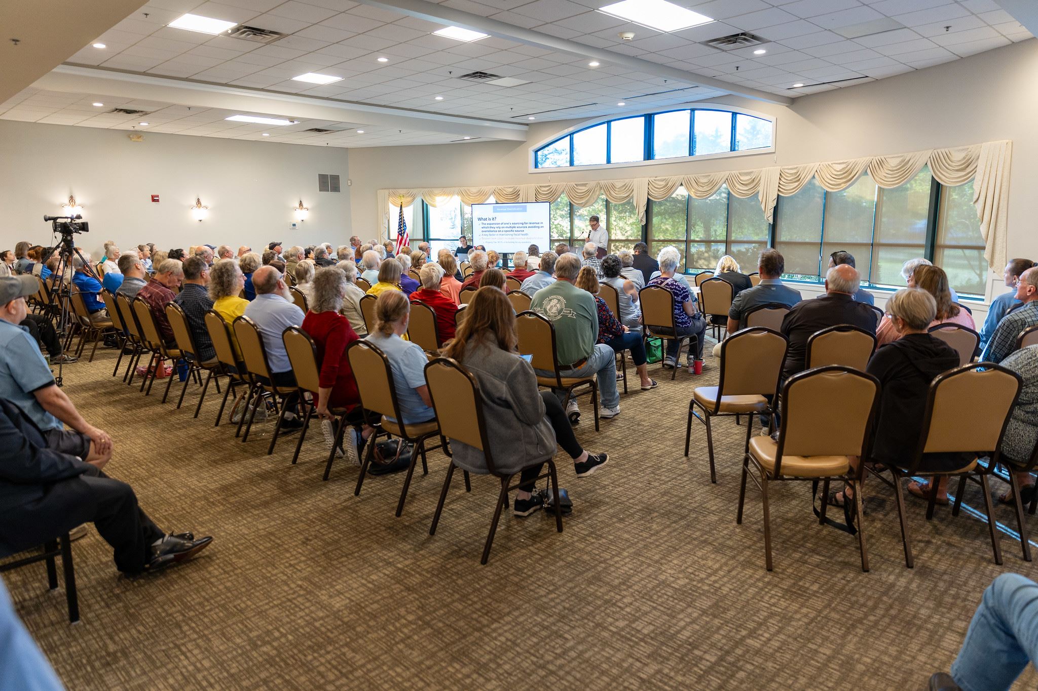 A crowded room of people for a town hall and presentation 